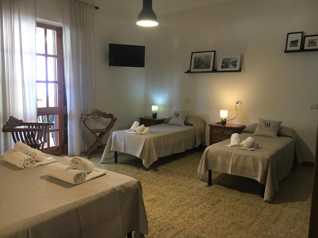 a room with three beds with towels on them at Mille Soli Bed and Breakfast in Buggerru