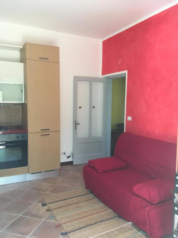 salon z czerwoną kanapą i kuchnią w obiekcie A casa di Andre’ w mieście Vara Superiore