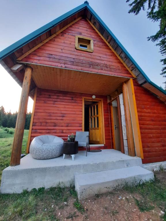 eine rote Hütte mit einer großen Veranda auf einem Feld in der Unterkunft Etno house Momcilo in Žabljak
