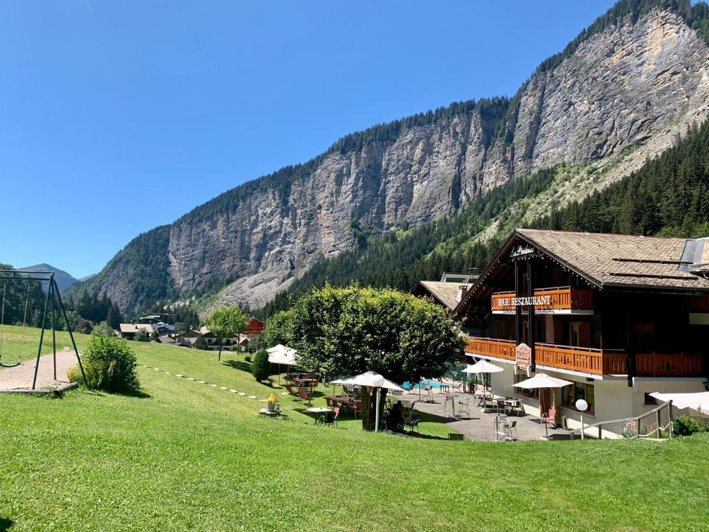 ein Gebäude auf einem Feld neben einem Berg in der Unterkunft Hameau des Prodains - Hôtel in Morzine