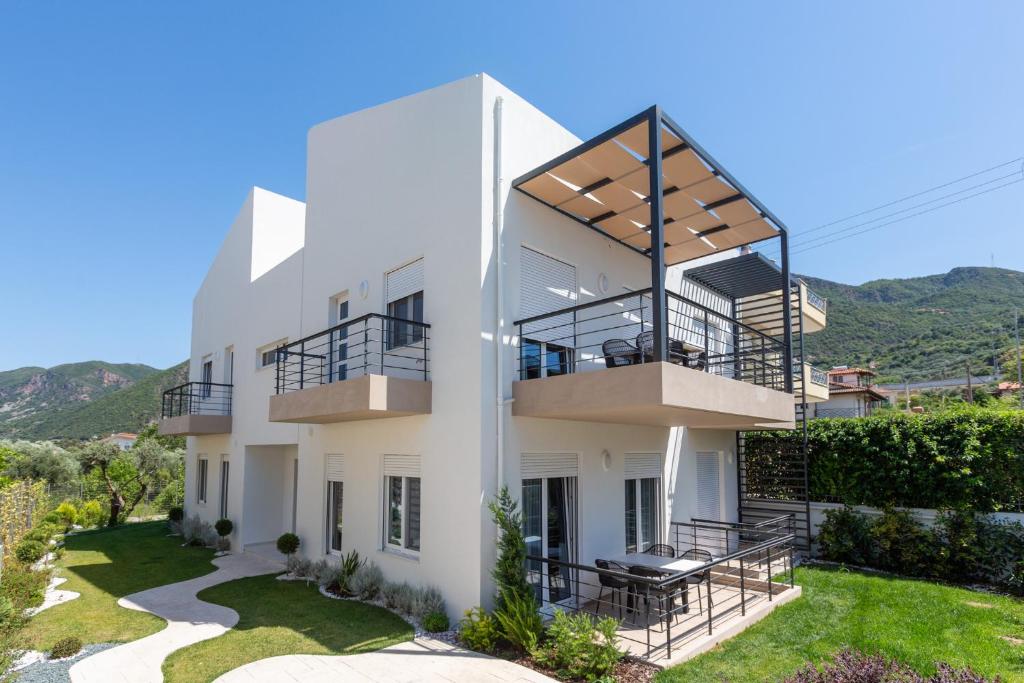 ein weißes Haus mit einem Balkon und einem Hof in der Unterkunft Two Olive Trees - Deluxe Apartments in Psathopyrgos