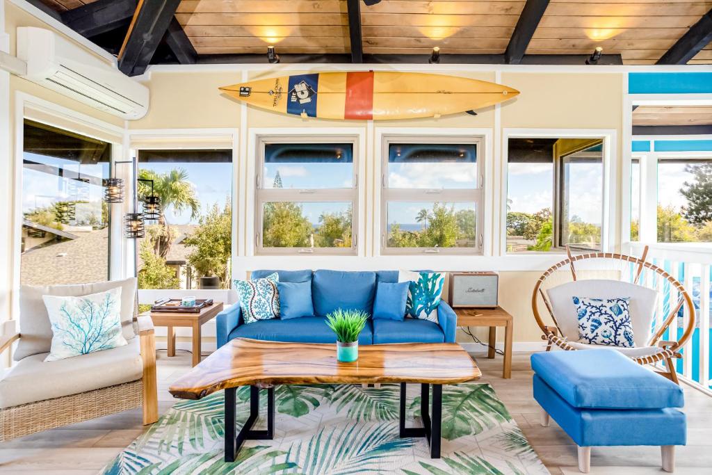 a living room with a blue couch and a surfboard on the wall at View House Tower! in Princeville