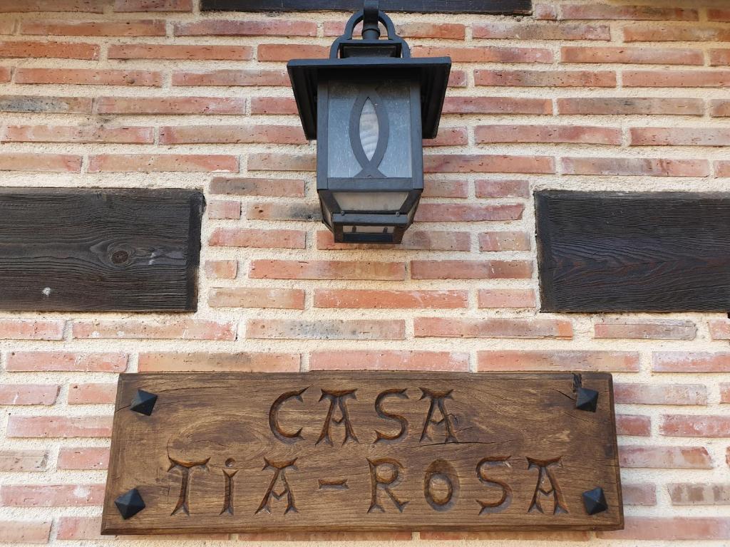 una señal en el lateral de un edificio de ladrillo con una luz de la calle en casaruraltiarosa, en Quintanilla del Agua