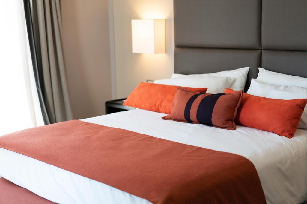 um quarto com uma cama grande e almofadas laranja em Carles Hotel em Buenos Aires