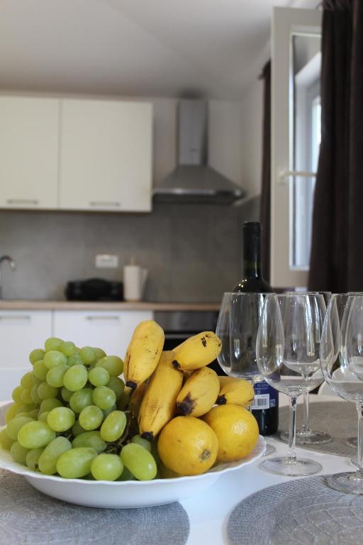 a plate of fruit on a table with wine glasses at Guest house Ada in Galižana