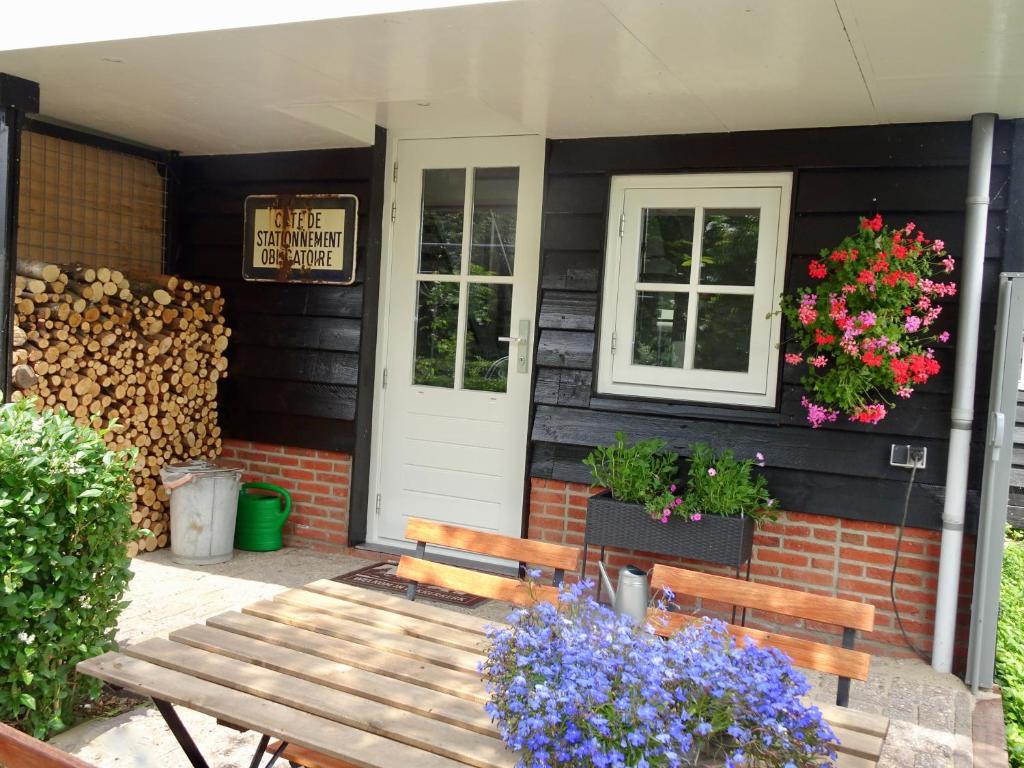 a wooden bench sitting outside of a house with flowers at De Kopstoof in Lekkerkerk