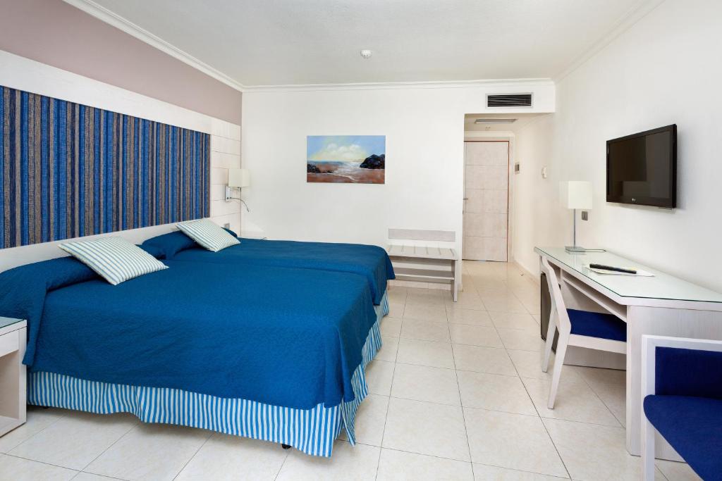 a bedroom with a blue bed and a desk at Tigotan Lovers & Friends Playa de las Americas - Adults Only (+18) in Playa de las Americas