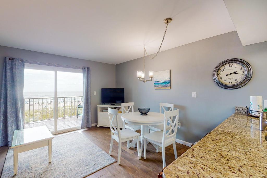a dining room with a table and a clock on the wall at Seacrest #202 in Gulf Shores