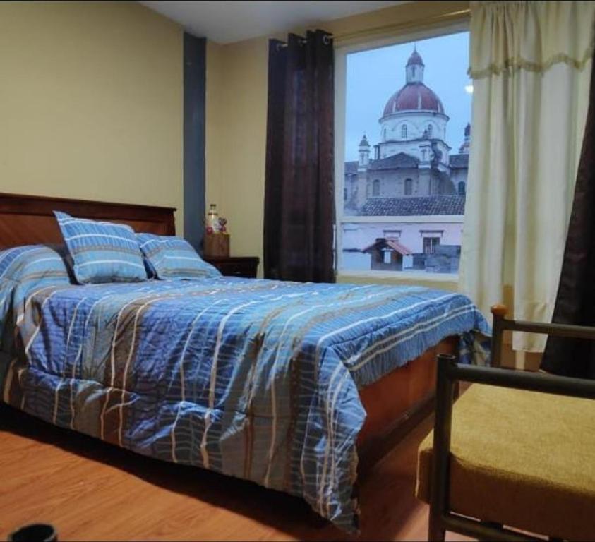 a bedroom with a bed with a view of a building at Hospedaje Wiruyana in Cotacachi