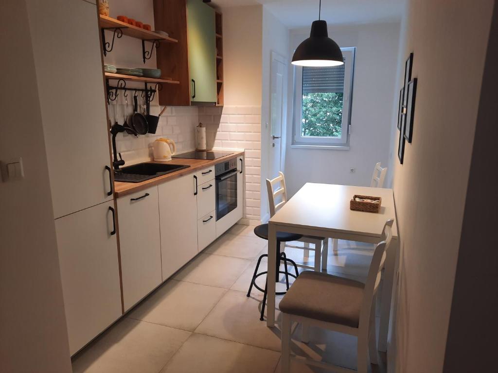 a kitchen with white cabinets and a table with chairs at Babalina's Place in Bihać