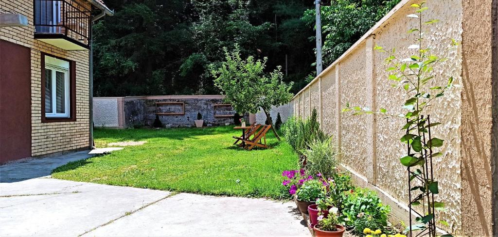 einen Garten mit einer Bank und Blumen neben einer Wand in der Unterkunft Sunčana Kuća in Krupanj