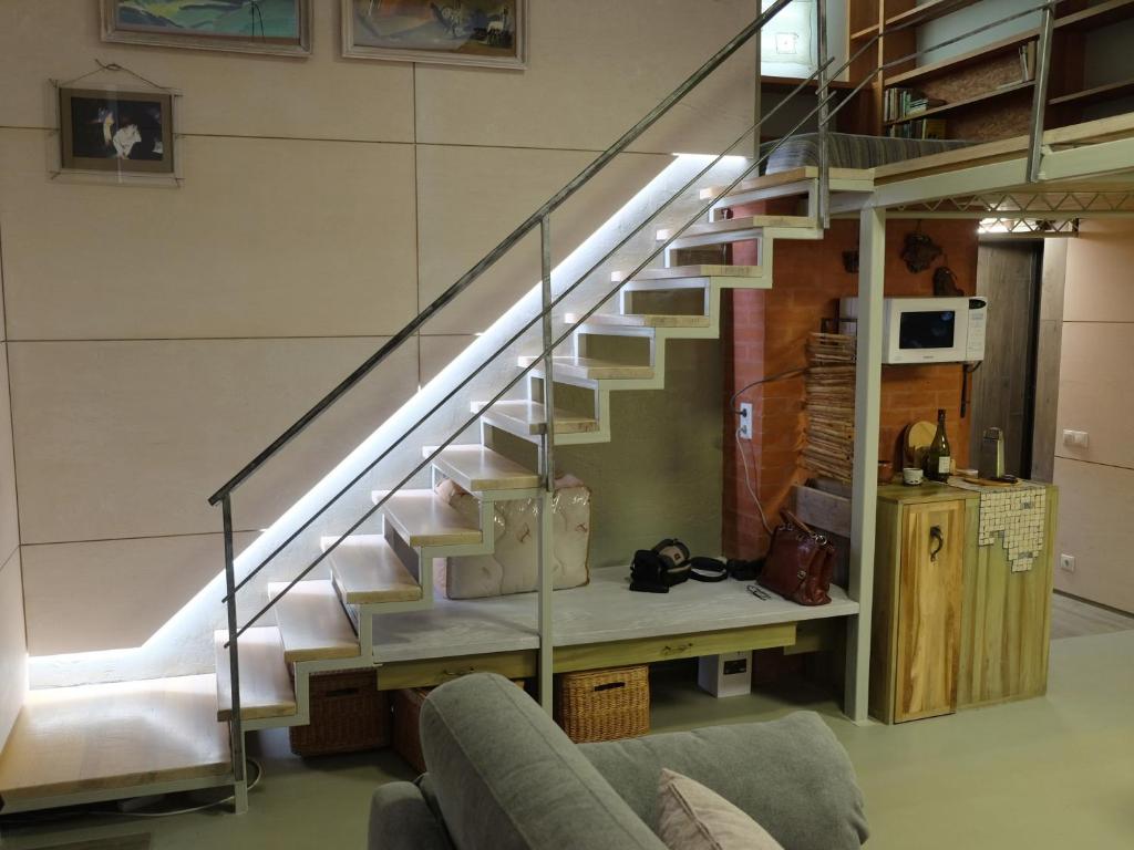 eine Treppe in einem Wohnzimmer mit Sofa in der Unterkunft Студія з внутрішнім півповерхом. in Mykolajiw