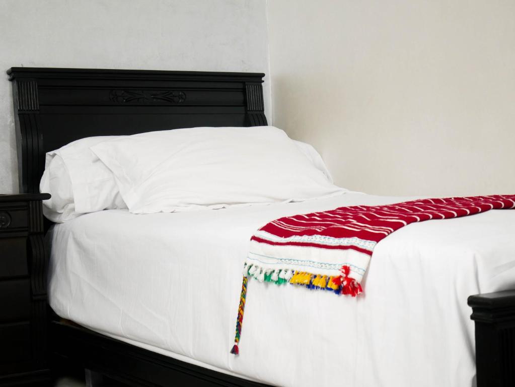a white bed with a red and white blanket on it at Ayouz House Hotel in Dakhla