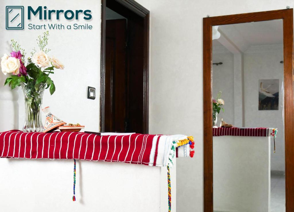 a vase of flowers on a table with a mirror at Ayouz House Hotel in Dakhla