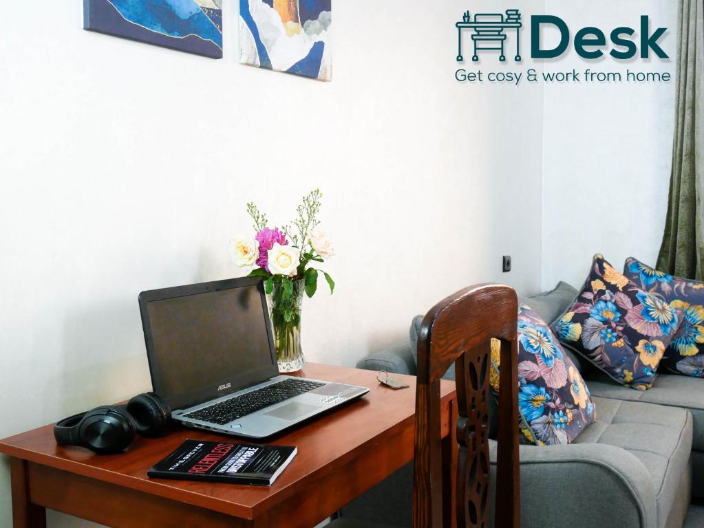 a desk with a laptop and a vase of flowers at Ayouz House Hotel in Dakhla