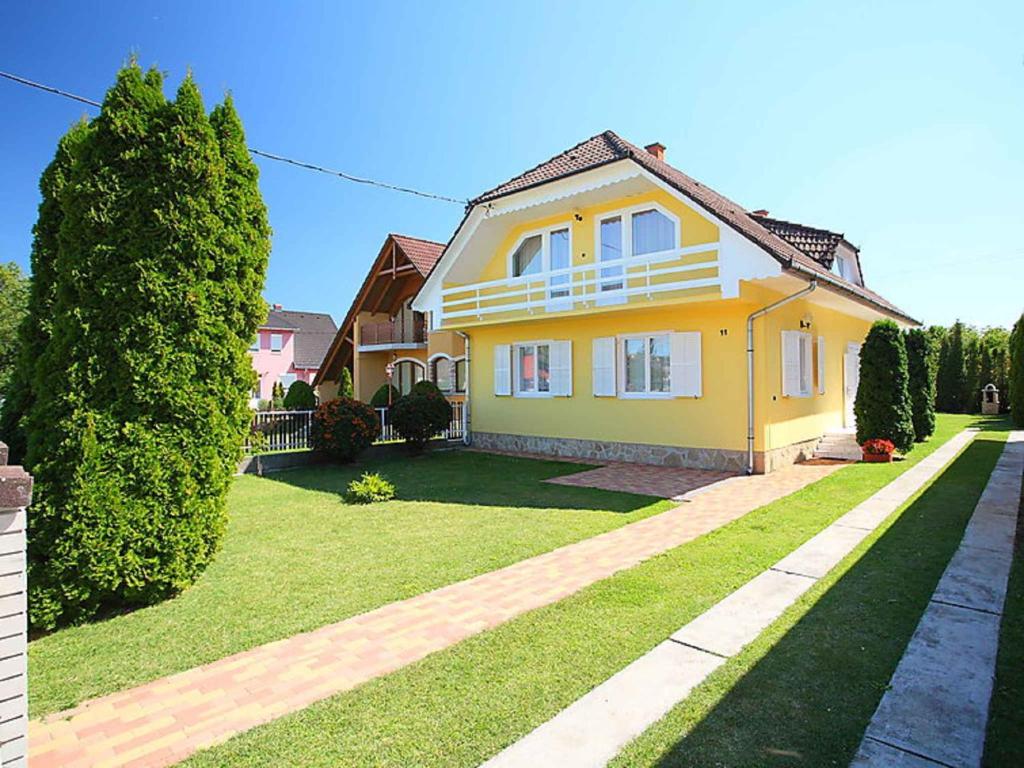 una casa amarilla con un patio verde en Holiday home in Balatonlelle 40449 en Balatonlelle