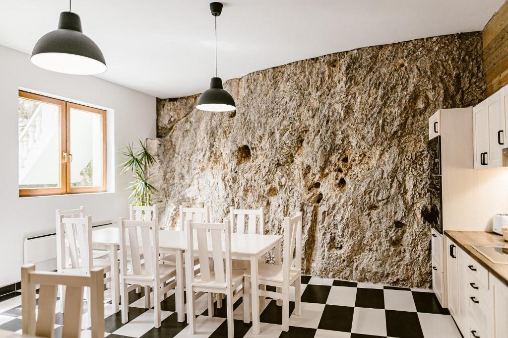 cocina con mesa, sillas y pared de piedra en sziklavendeghaz en Veszprém