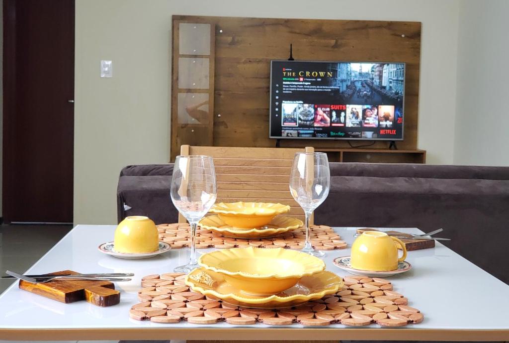 uma mesa com pratos amarelos e copos de vinho em TH 3406 - Flat de Três Quartos em Governador Valadares