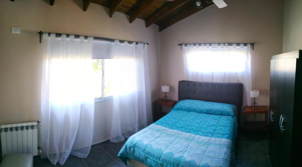 a bedroom with a bed and two windows at Departamento Cerro Negro in Villa General Belgrano