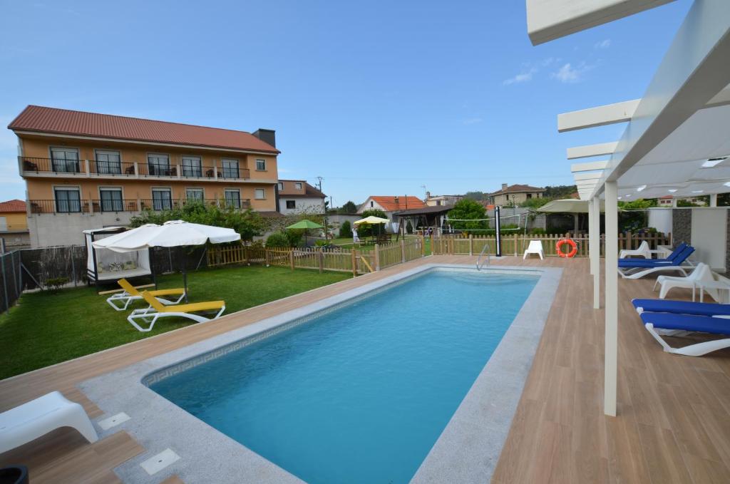 una piscina con sillas y un edificio en Hotel Cachada, en Sanxenxo