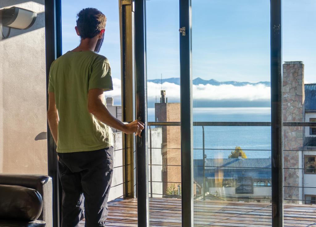 un hombre mirando por una ventana al océano en Belgrano Decks, en San Carlos de Bariloche