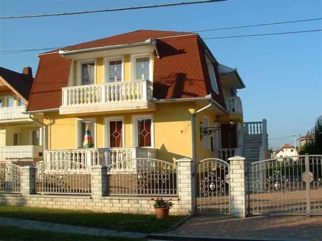 ein gelbes Haus mit einem Zaun davor in der Unterkunft Apartments in Zalakaros 38691 in Zalakaros