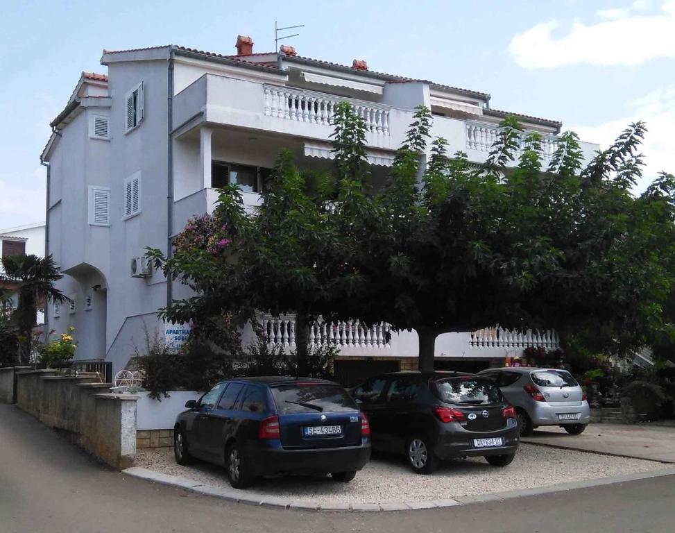 due auto parcheggiate in un parcheggio di fronte a un edificio di Apartment in Zadar/Zadar Riviera 8183 a Smirić