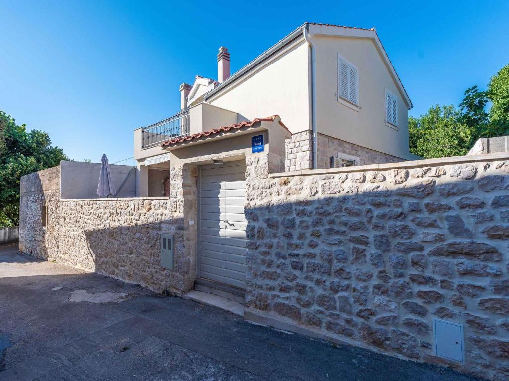 a house with a garage and a stone wall at Holiday home Kozino/Zadar Riviera 33795 in Kožino