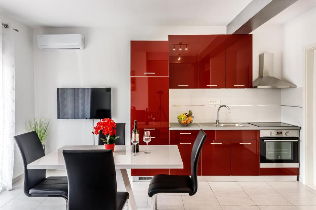 a kitchen with red cabinets and a white table and chairs at Luxury apartments Budimir in Podstrana