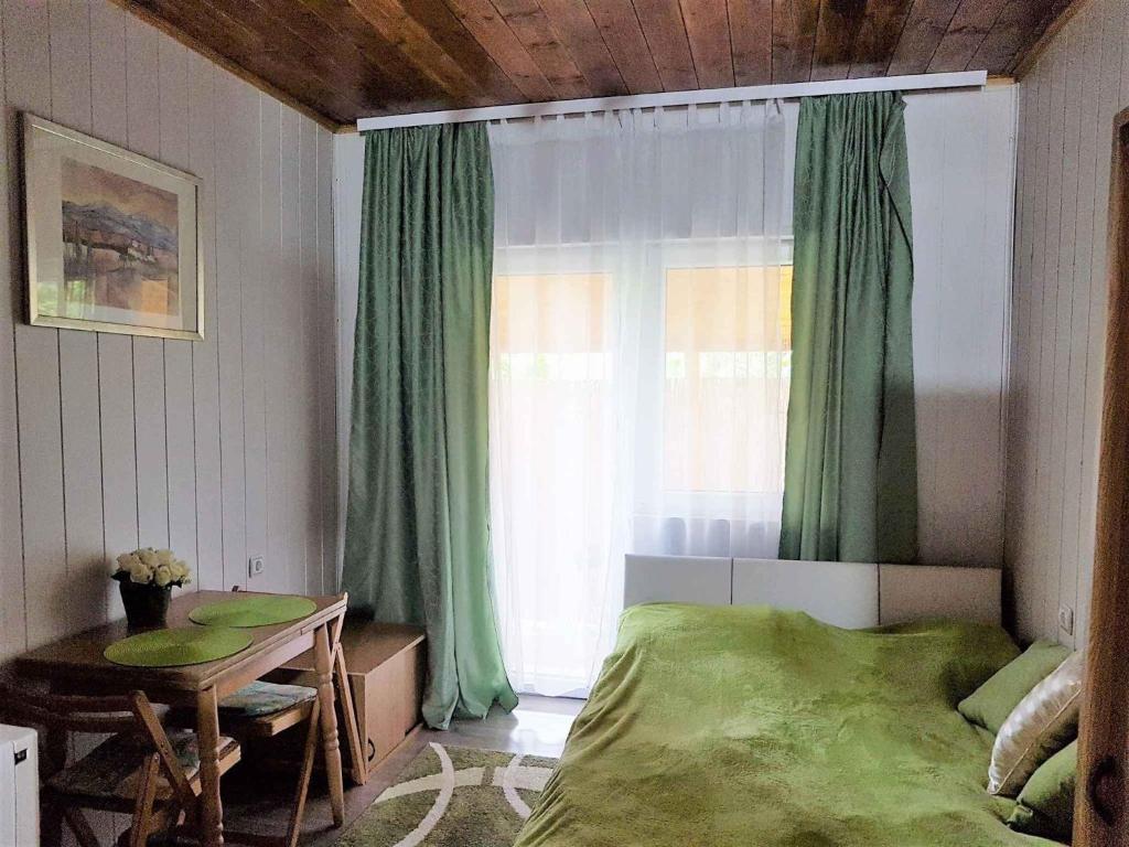 バラトンアカリにあるHoliday Homes in Balatonakali 37748のベッドルーム1室(ベッド1台付)、窓(緑のカーテン付)