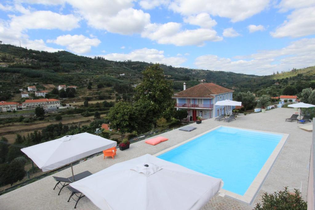 a swimming pool with two umbrellas and a house at Quinta da Tapada in Avô
