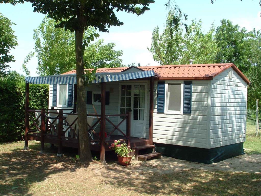 a small shed with a porch and a tree at Mobilehomes in Cavallino-Treporti 33773 in Cavallino-Treporti