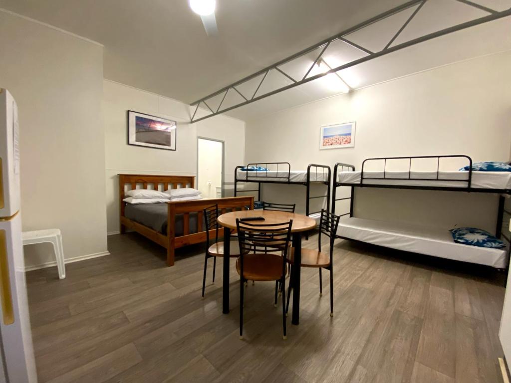 班達伯格的住宿－Bundaberg Park Village，客房设有两张双层床和一张桌子及椅子。