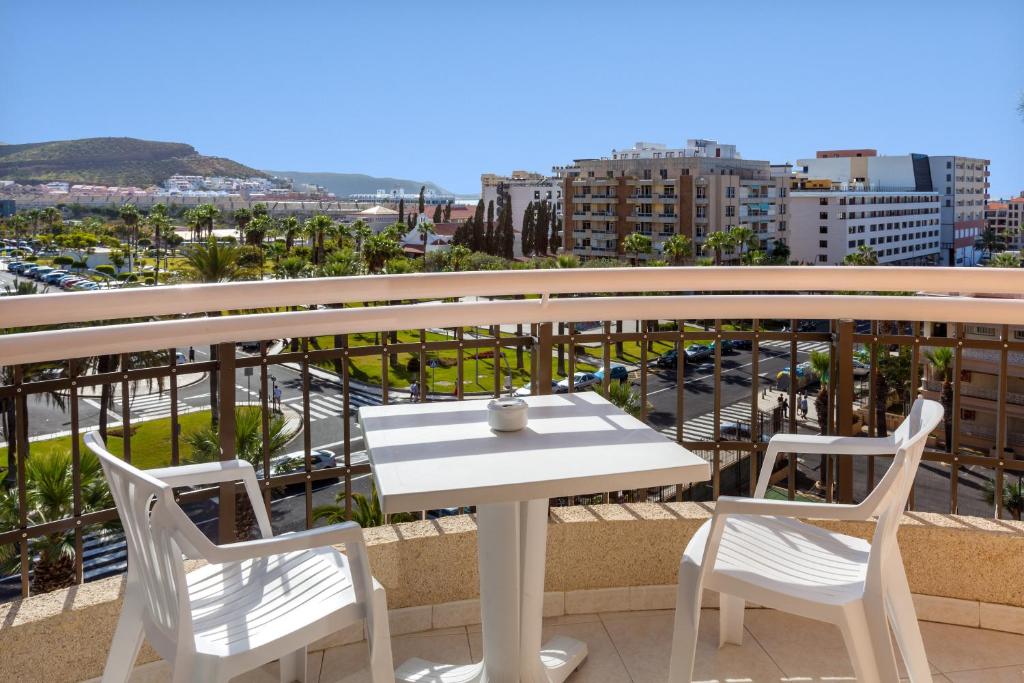 a white table and chairs on a balcony with a city at Tigotan Lovers & Friends Playa de las Americas - Adults Only (+18) in Playa de las Americas