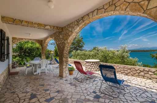 un patio con sillas, una mesa y una pared de piedra en Apartment in Klimno/Insel Krk 14302, en Klimno