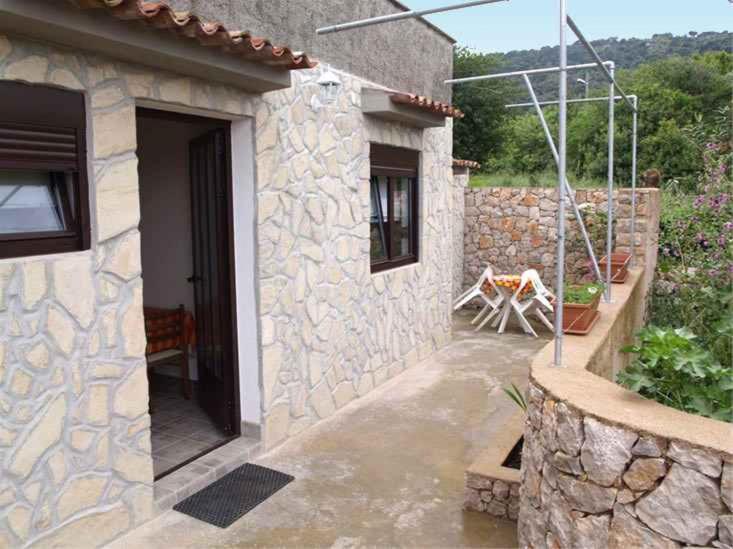 a house with a stone wall and a patio at Apartment in Veli Losinj 33734 in Veli Lošinj