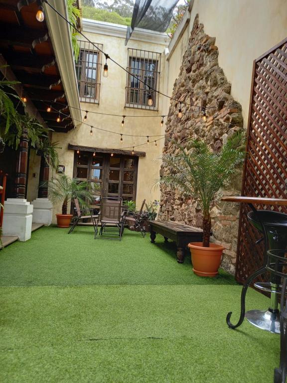 a patio with a stone wall and green grass at Casa Catalina in Antigua Guatemala