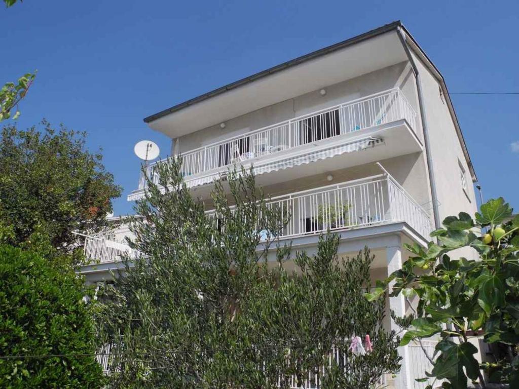 a white building with white balconies and a clock at Apartment in Selce 5818 in Selce