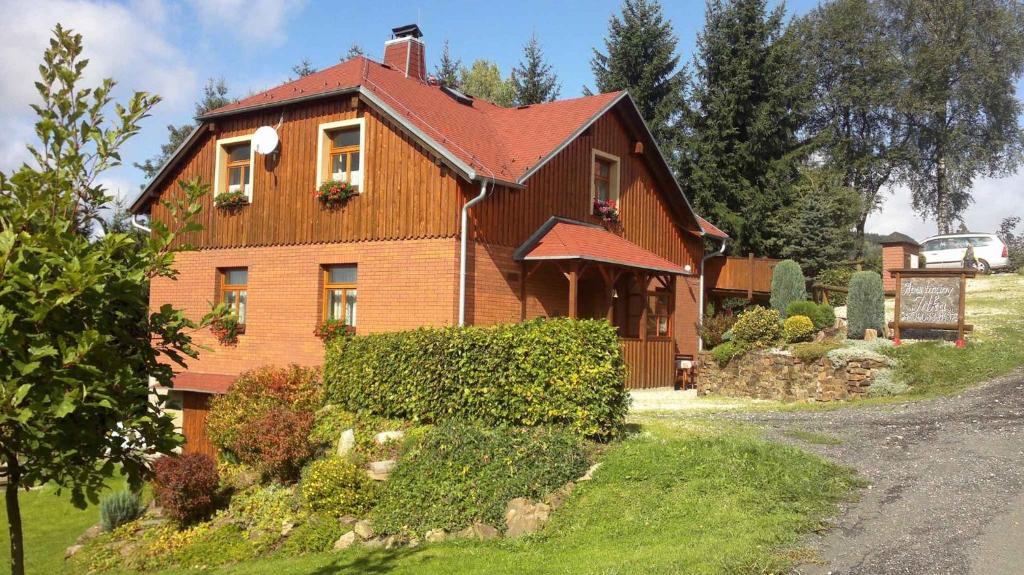 une grande maison en bois avec un toit rouge dans l'établissement Apartments in Bublava/Erzgebirge 1704, à Bublava