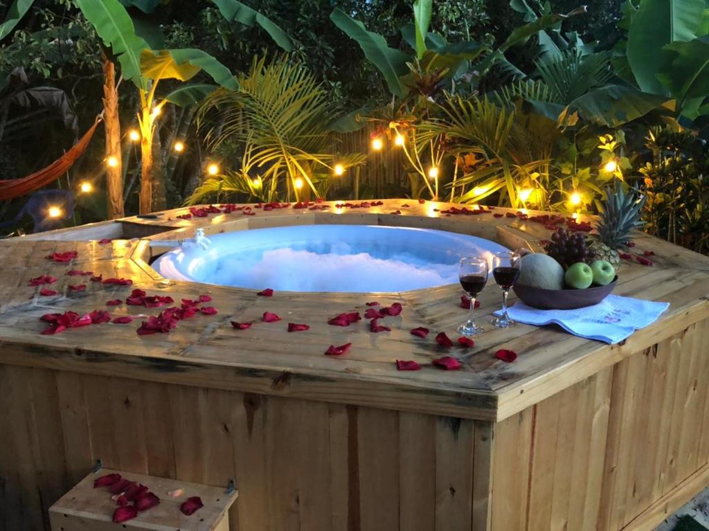 bañera de hidromasaje con mesa, copas de vino y rosas en Paraíso Glamping La Vega, en La Vega