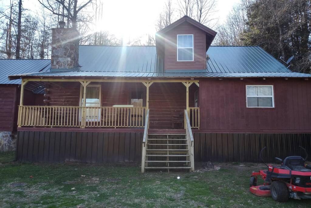ein großes rotes Haus mit einer Veranda und einer Terrasse in der Unterkunft Hoot Nanny's Rustic Cabin on Mossy Creek in Cleveland