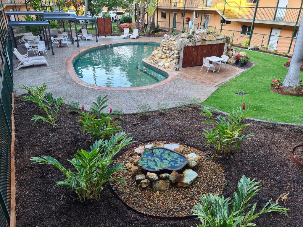 a backyard with a pool with a table and chairs at Alatai Holiday Apartments in Darwin