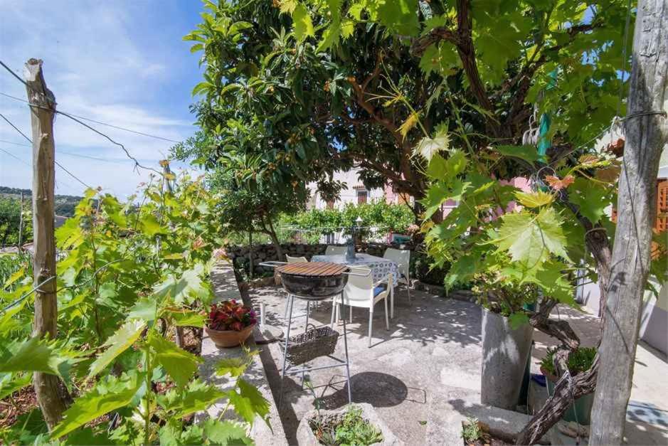 a patio with a table and chairs and plants at Apartments in Veli Losinj 33624 in Veli Lošinj
