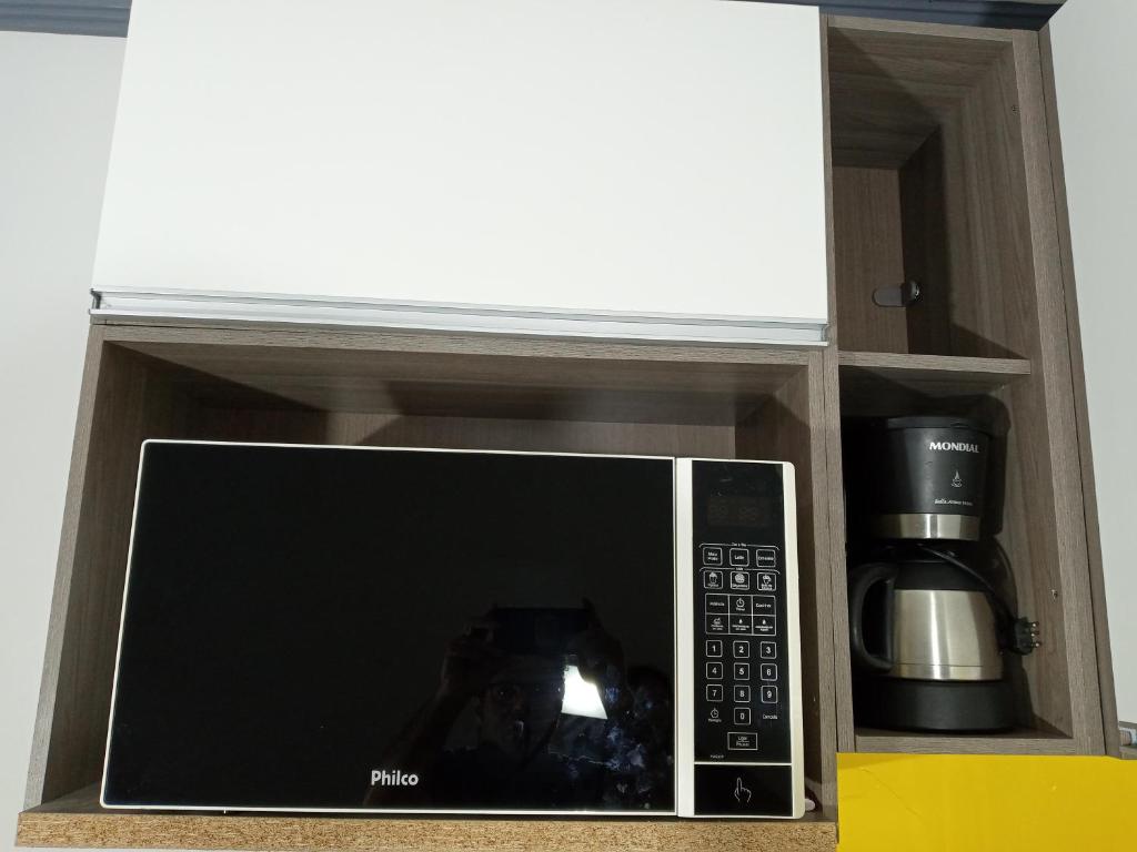 a microwave with a coffee mug in a cabinet at Apartamento no coração de Curitiba in Curitiba