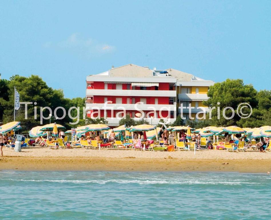 ビビオーネにあるApartments in Bibione 24559のビーチ沿いのホテル(椅子、パラソル付)