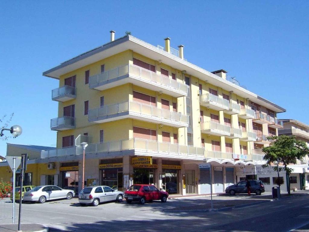 um grande edifício amarelo com carros estacionados num parque de estacionamento em Apartments in Eraclea Mare 25693 em Eraclea Mare