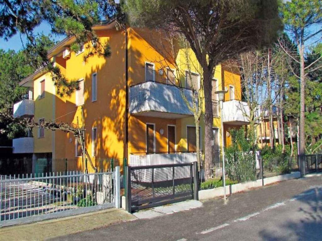 una casa gialla con una recinzione di fronte di Apartment in Bibione 24631 a Bibione