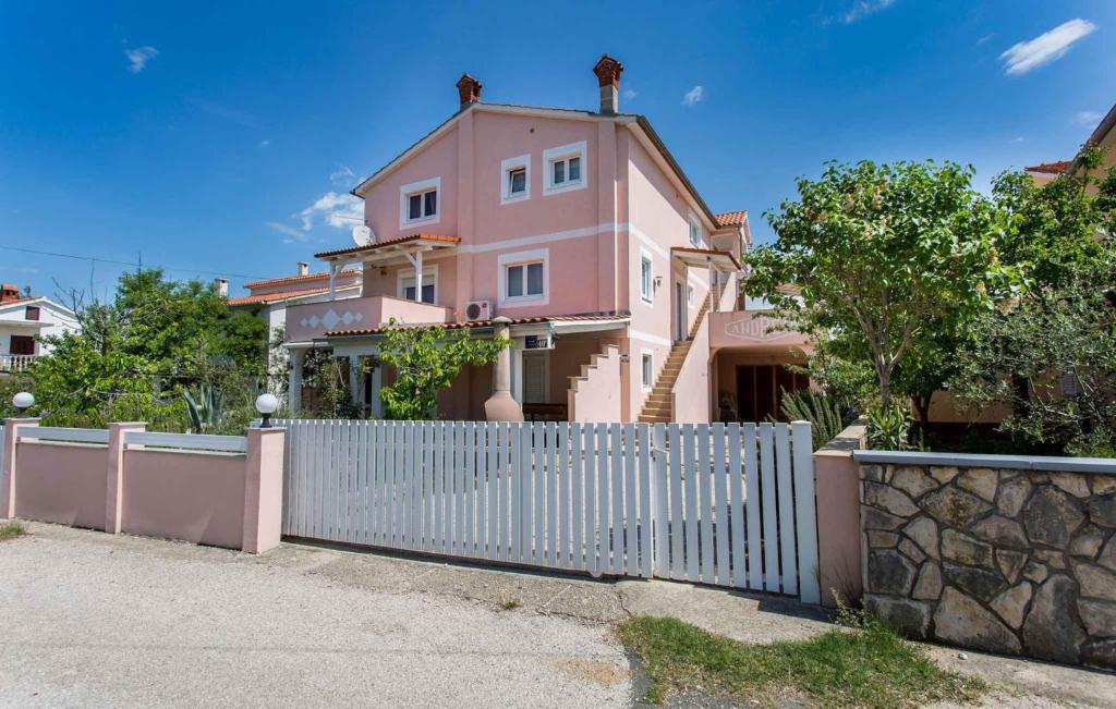 ein rosafarbenes Haus mit einem weißen Zaun davor in der Unterkunft Apartment in Silo/Insel Krk 13488 in Šilo