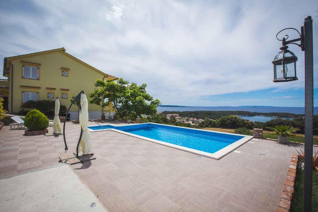 a swimming pool in front of a house at Apartments in Rab/Insel Rab 16117 in Mundanije