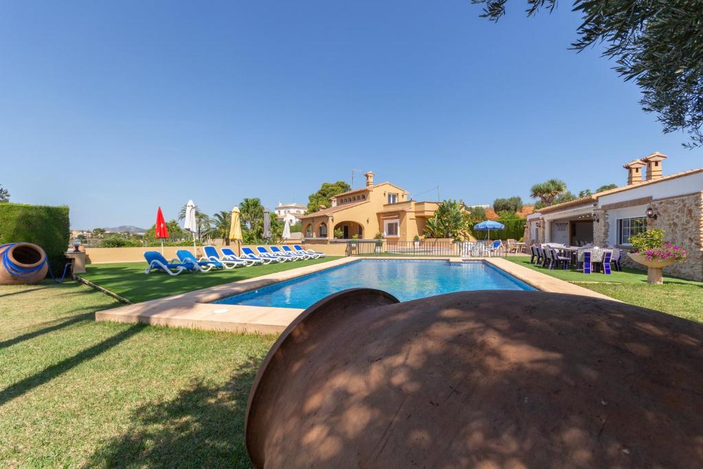 une grande piscine avec des chaises et une maison dans l'établissement Villa Benimarco - Costa CarpeDiem, à Teulada